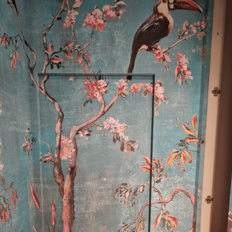 Porta a filo muro rivestita con la stessa carta: il tronco e i fiori proseguono senza interruzioni