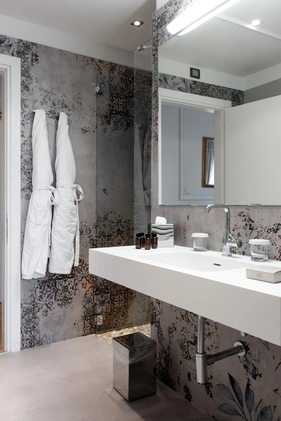 Bagno con carta da parati effetto cemento e maioliche dietro lavabo e doccia