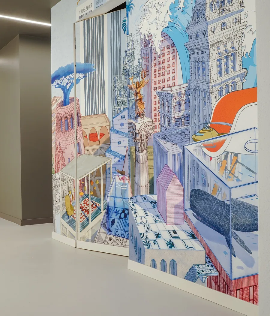 Ufficio con parete e porta a filo muro rivestite da un murale illustrato di palazzi e grattacieli